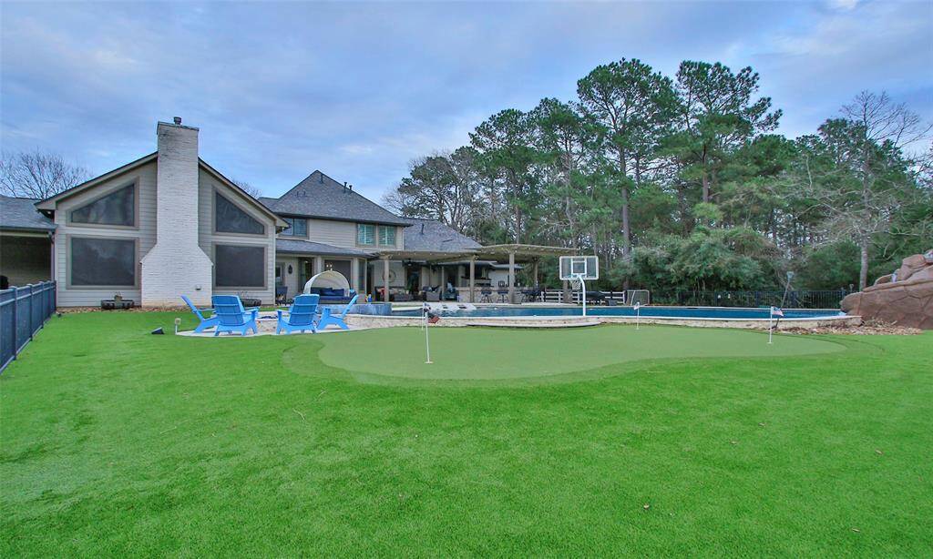 This spacious backyard features a modern home with a large patio, a swimming pool with a basketball hoop, and your own putting green. Surrounded by mature trees, it offers a private and recreational outdoor space.