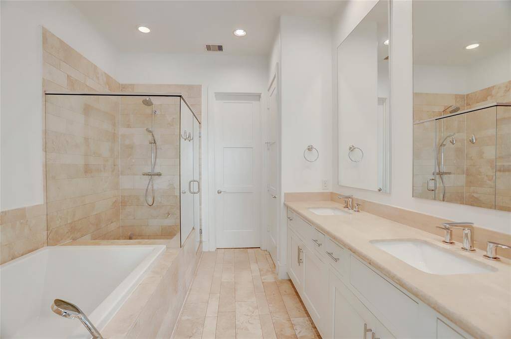 The primary bath, which includes a glass shower, soaking tub with detachable showerhead, double sinks, and a water closet.