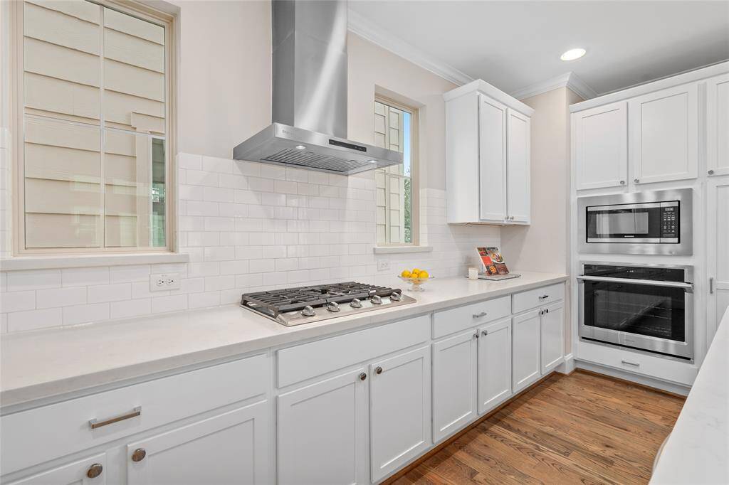 Close-up view of the white subway-style backsplash and gas cooktop. The stainless cooktop and vent hood back up to an exterior wall, which is ideal for ventilation.