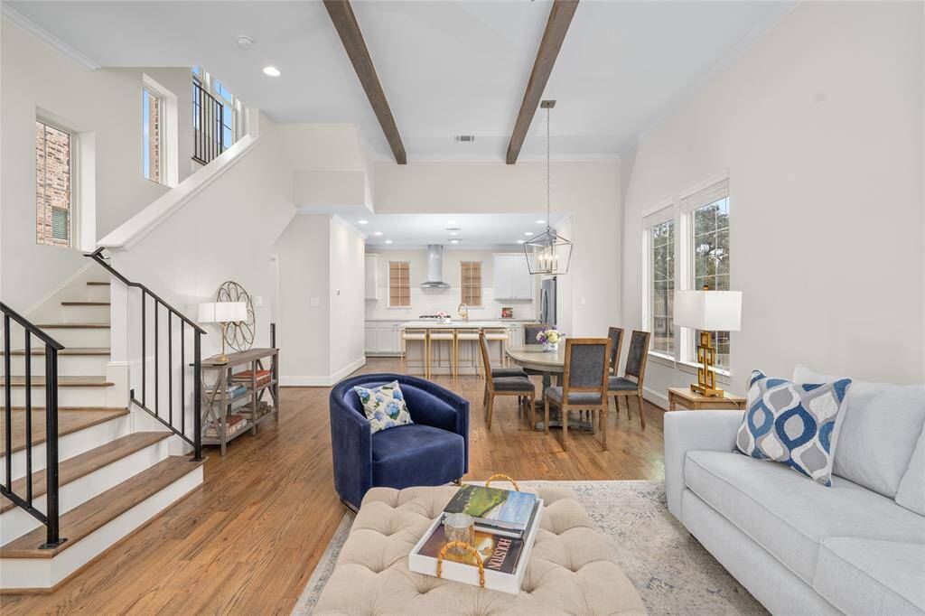 Beautiful photo of the living and dining areas with the kitchen beyond. Notice the abundance of natural light emanating through the numerous windows and the gorgeous hardwood flooring.