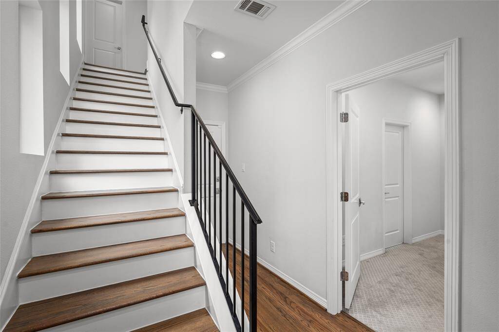 The staircase leads up to the second level. This photo provides a sneak peek into the first-floor bedroom suite. The hallway ends at a secure door of the two-car attached garage.