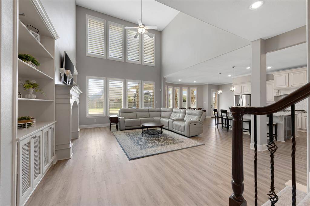 The spacious family room is truly impressive, with soaring tall ceilings that create an open, airy feel. A stunning 2-story wall of windows floods the room with natural light, offering breathtaking views of the outdoors. Built-in cabinets and shelving provide both functionality and style, while the cozy gas-log fireplace adds warmth and ambiance, making it the perfect place for relaxation or entertaining.
