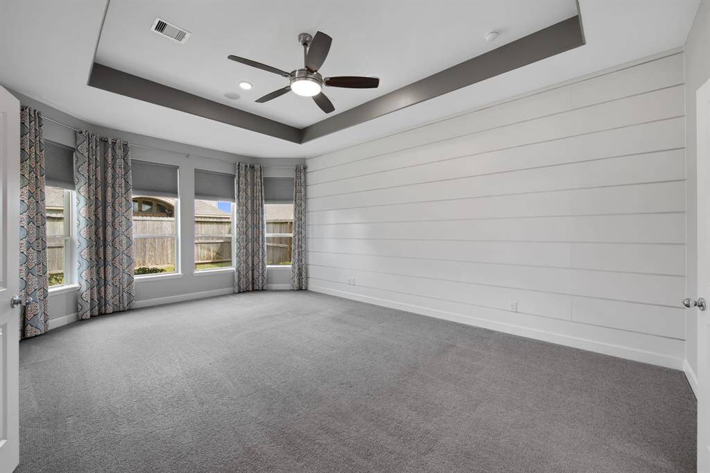 The oversized Primary Bedroom includes upgrades such as: the extra square footage that comes with a bay window accented with custom designer window treatment, wide "shiplap"wall treatment ($1,750.00), a specialty tray ceiling with accent paint, a Kichler Trevor II LED 60" Ceiling Fan ($437.00), and 4 recessed can fixtures ($720.00) The carpet, where located in the house, is stain resistant protected over a 1/2" pad.