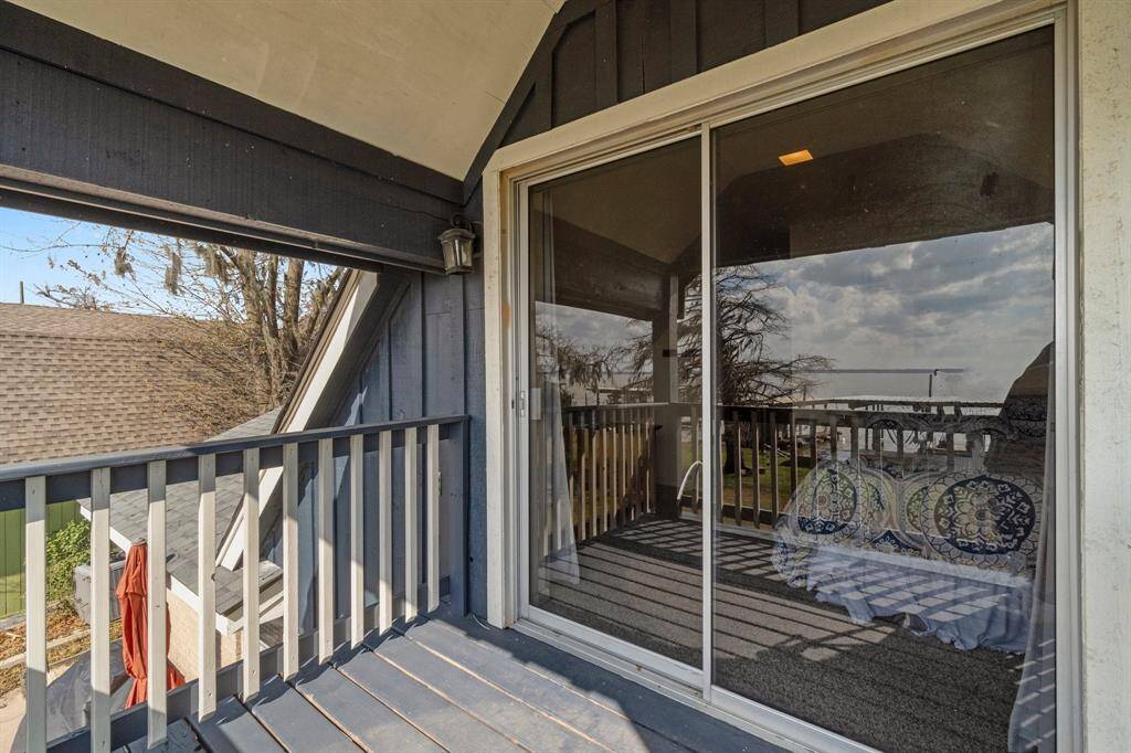 This photo showcases a cozy balcony with wooden railings and a sliding glass door, offering a private outdoor space with a view of the surrounding area, perfect for relaxation.