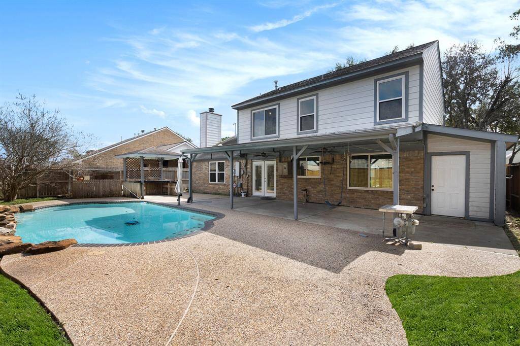 This amazing backyard showcases a sparkling pool, a big covered patio area and a storage shed.