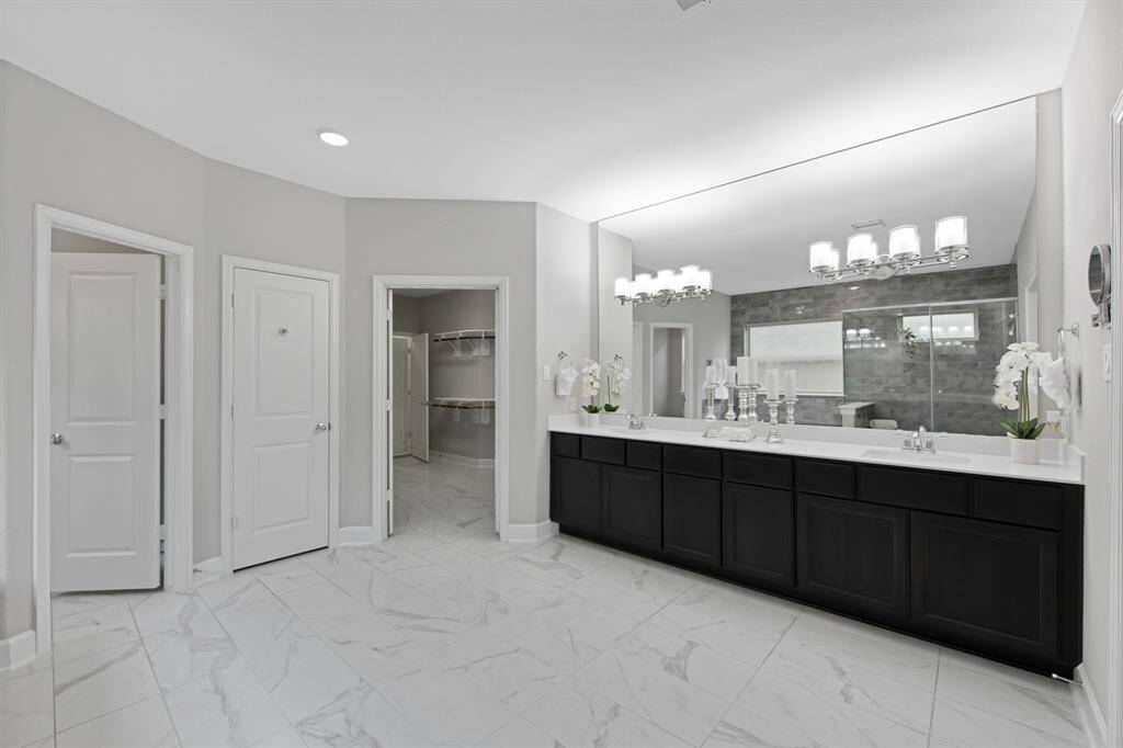 The tile floors in the Primary Bathroom and Primary Closet are large rectangle white and gray ceramic tile ($2,445.00). There are 2 rectangle cultured marble sinks with square edges ($600.00). The vanity mirror goes to the ceiling ($300.00) and is accented with 2 (4 bulbs each) fixtures ($314.00).