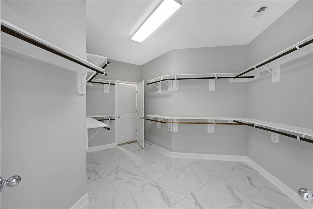 A set of French doors lead to this very large Primary Closet which has built in shelves to the right of the door and an abundant amount of hanging space. The door in the middle leads to the laundry (utility) room.