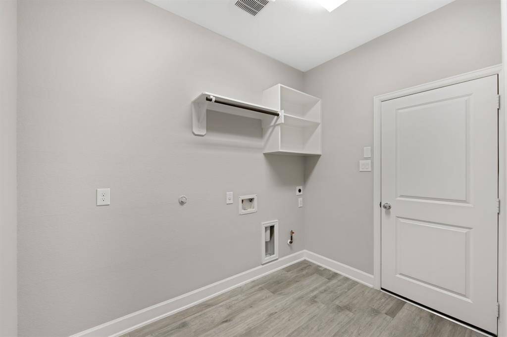 The laundry/utility room has plenty of room for a washer, dryer and second refrigerator.  There are built-in shelves, a hanging rod and plenty of space.  The door on the right leads to the garage.