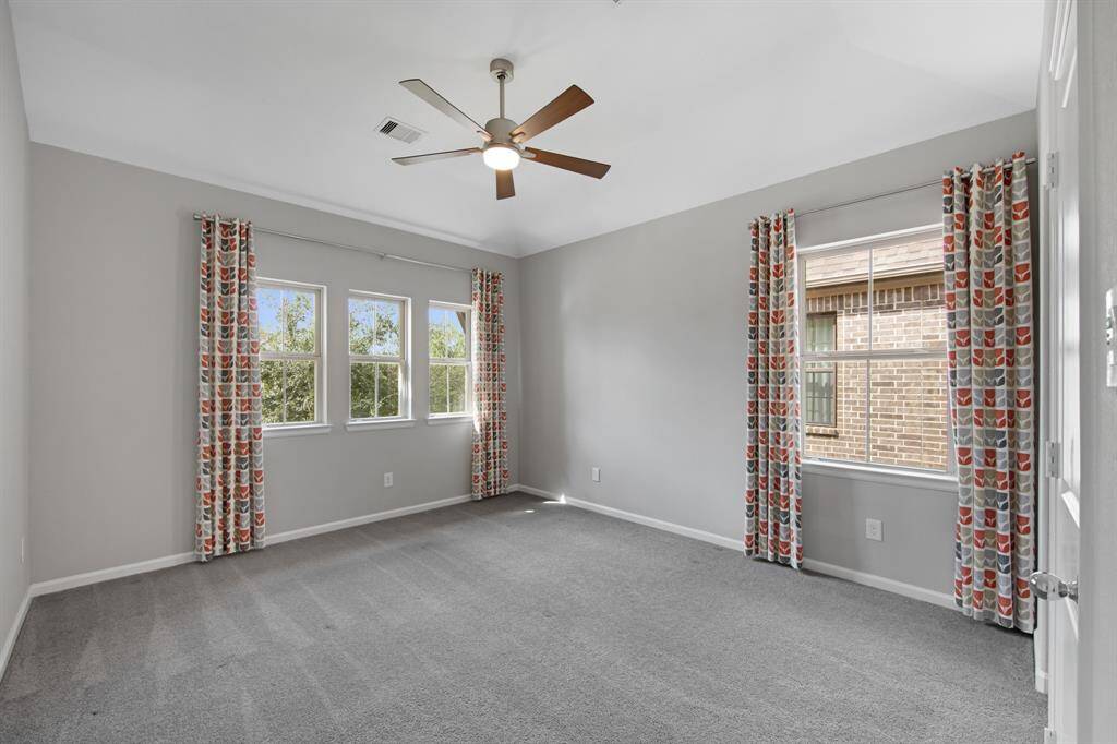 This upstairs secondary bedroom is located on the front side of the house and has custom designer window treatment as well as a Kichler Lucian LED 52" ceiling fan.