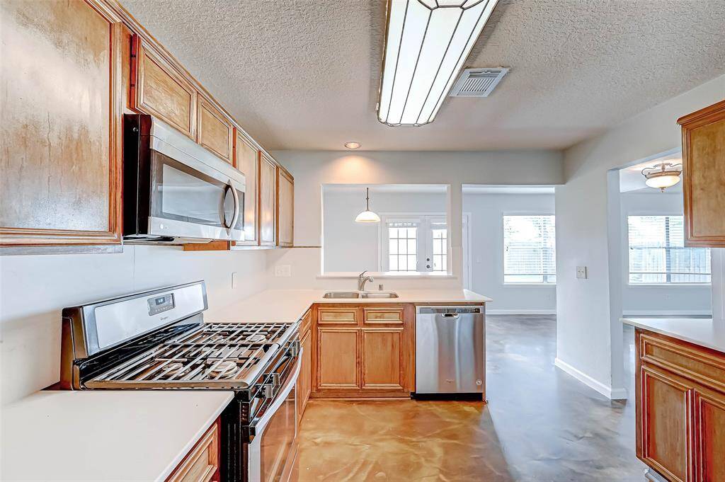 The open kitchen boasts neutral Quartz countertops, stainless steel appliances, and gas cooktop. Fridge included!