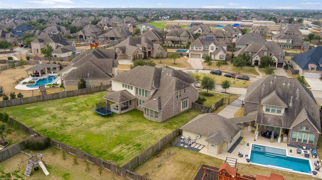 The aerial view of the home and its surrounding area captures the spaciousness of the property, with the nearby elementary school visible in the distance, offering a sense of community and convenience just a short distance away.