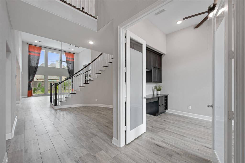 Off of the entry foyer are frosted glass French doors leading to the sizable office. The center light fixture has been upgraded to a ceiling fan with light kit along with 4 can lights.