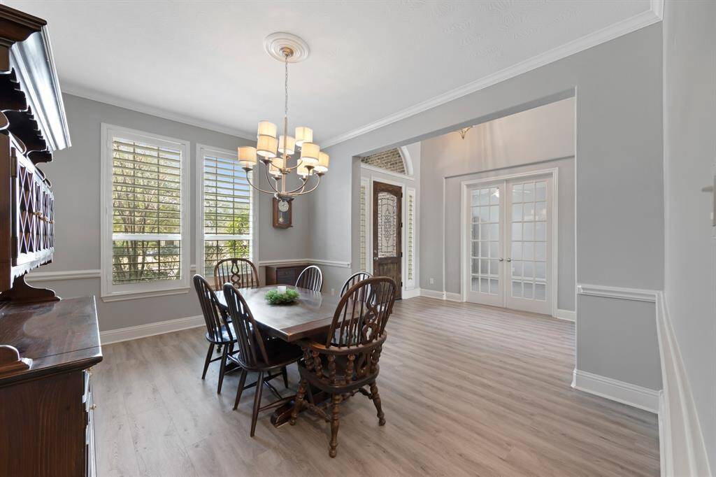 The formal dining room exudes sophistication with its exquisite crown molding and elegant chair rail, creating a refined atmosphere for every meal. A stunning chandelier hangs above, adding a warm, ambient glow and enhancing the room's timeless charm. It’s the perfect setting for both intimate dinners and grand gatherings.