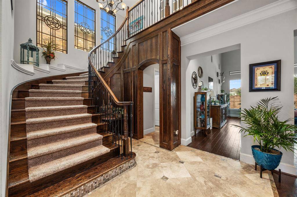 This elegant home features a grand entrance with a sweeping staircase and intricate wrought iron railing