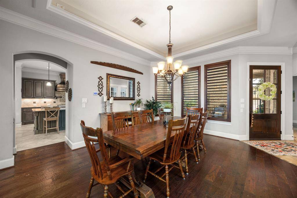 Dining has open layout with a view into the kitchen, hardwood floors, and ample natural light from large windows.