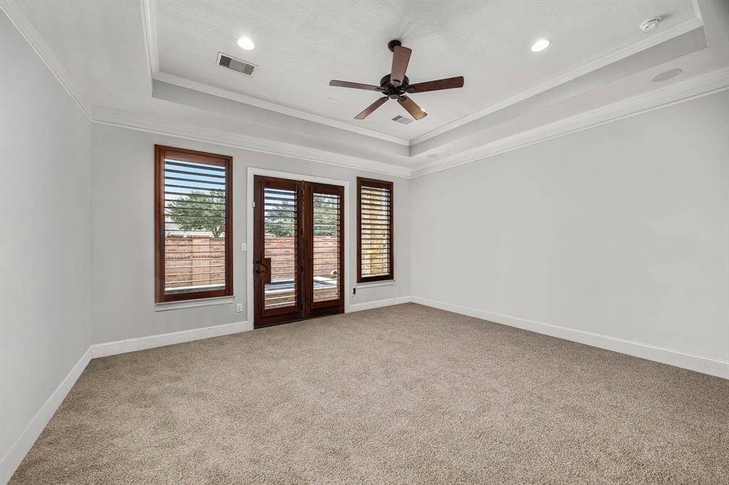 Elegant primary bedroom with French doors opening to a private hot tub and cocktail pool oasis.