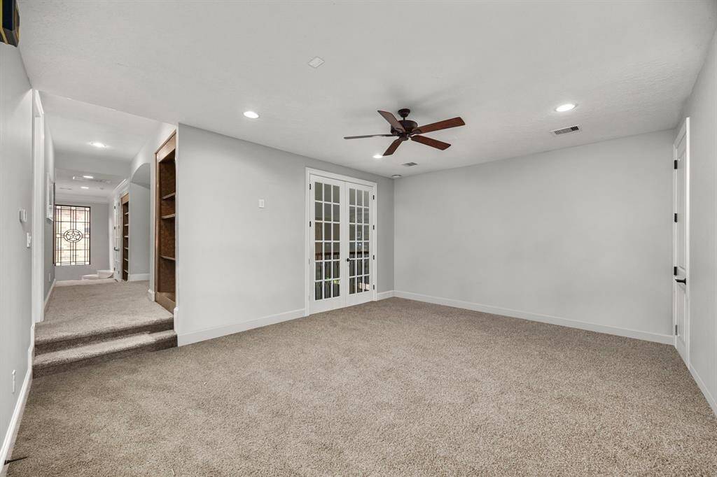 Spacious upstairs game room with a private balcony overlooking the living area, featuring doors for added privacy.