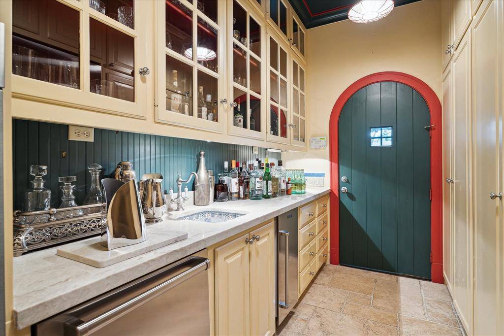 A combination kitchen extension and bar, this useful space has a beautiful custom sink, a dishwasher, refrigerator and coffee bar.  Notice the extensive storage.