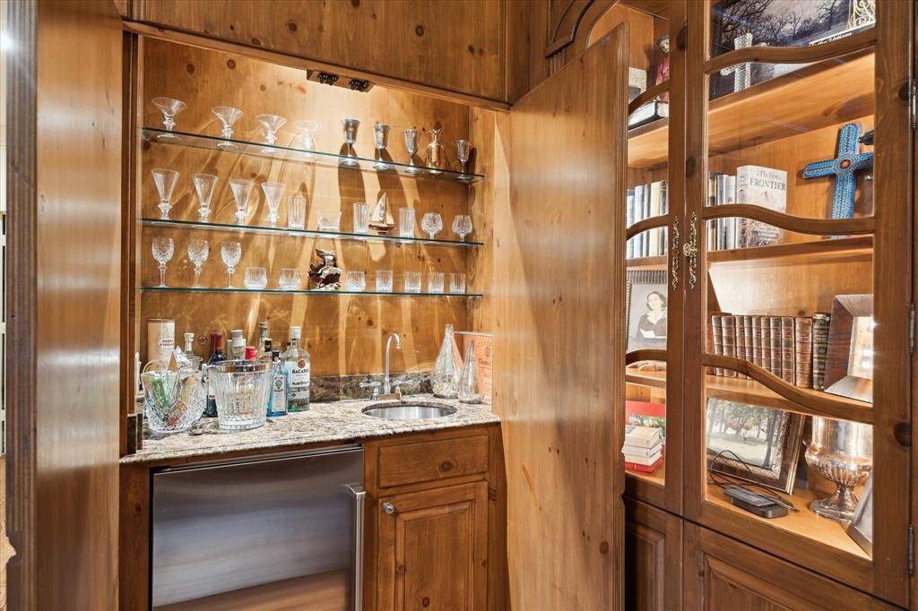 Opposite corner of the den features a bar and lighted display cabinets.