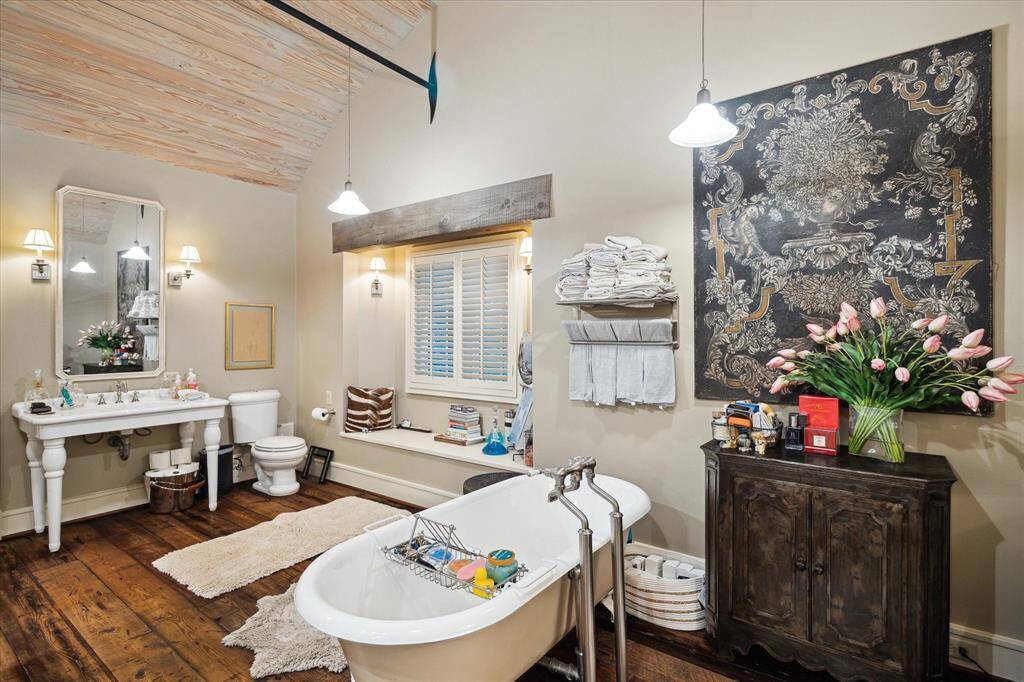 One of the primary baths with wash stand, soaking tub and window seat.  Note the rich wood floors and construction detail.