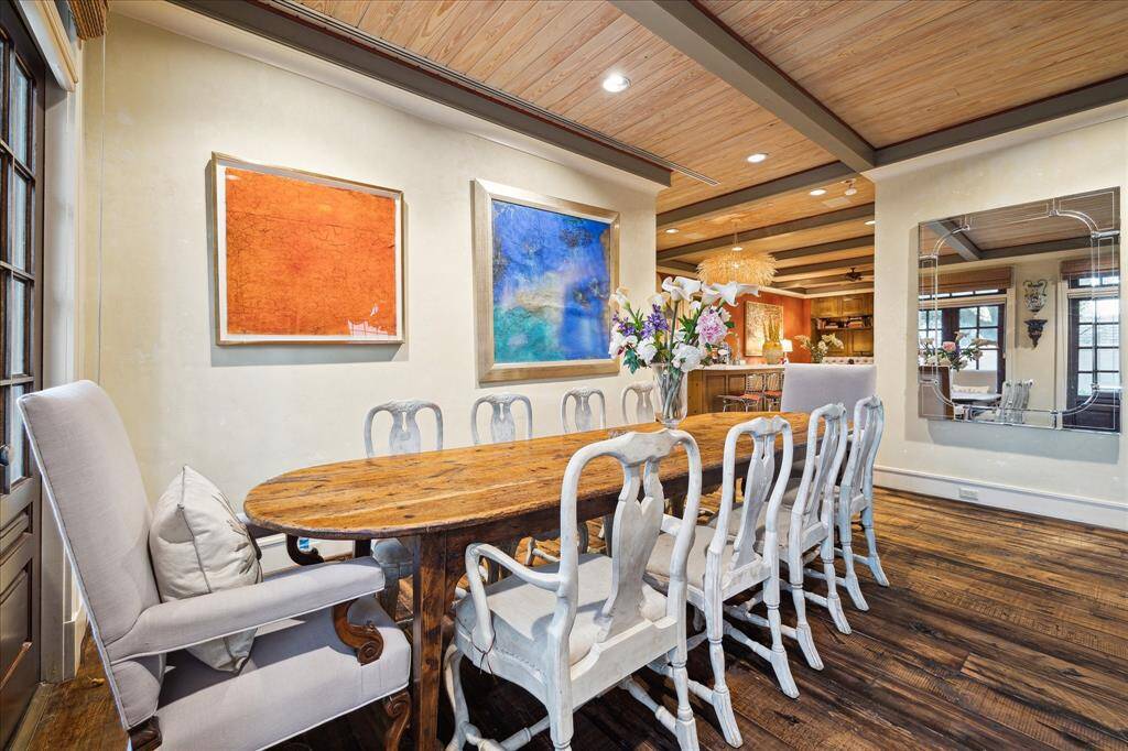The dining area is conveniently located near the kitchen and features wood floors, walls to display art and a wood accented beamed ceiling.