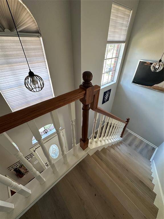 High foyer with hanging fixture and arched window; additional window in stairwell