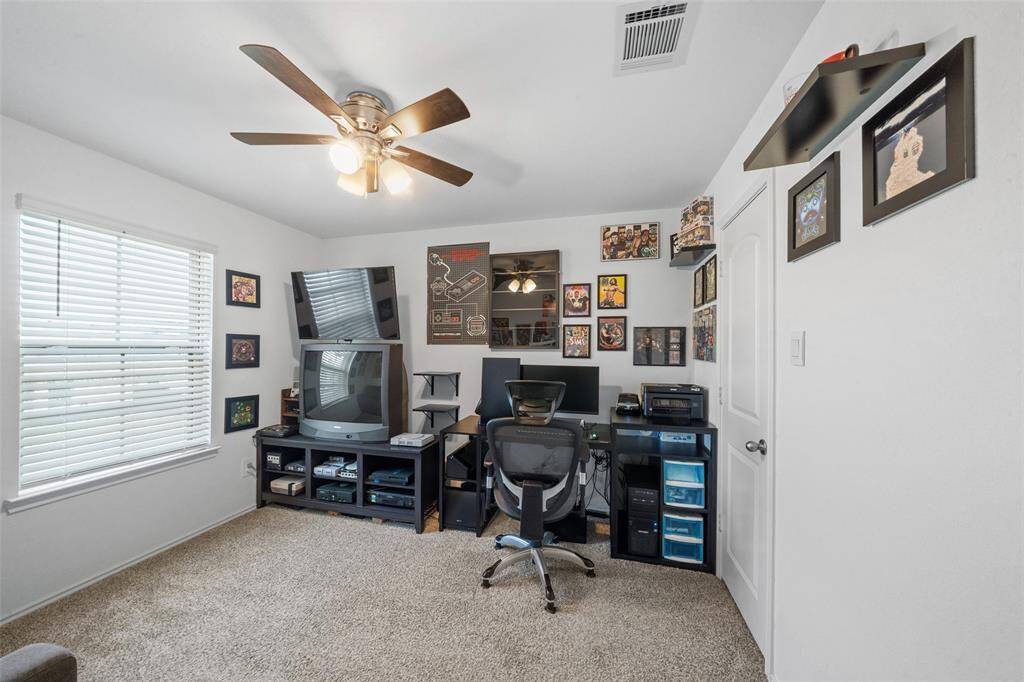 Secondary bedroom with large window, lush carpet, sizable closet and ceiling fan.