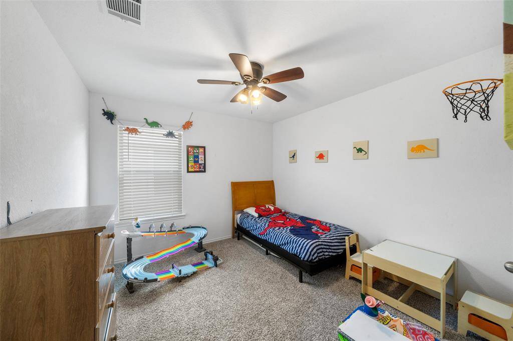 Secondary bedroom with large window, lush carpet, sizable closet and ceiling fan.
