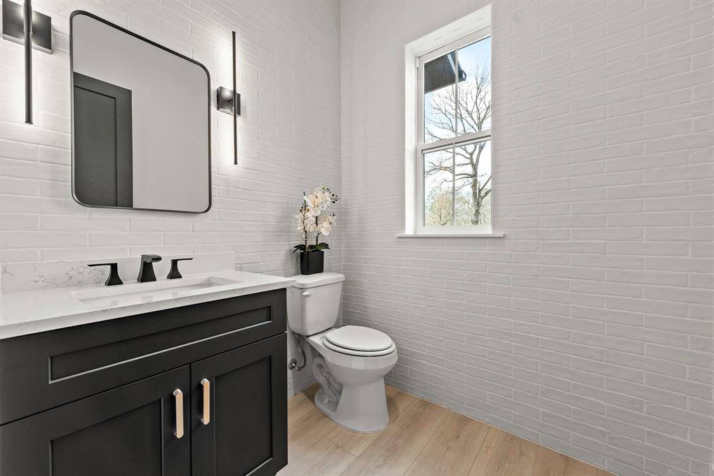 Downstairs half bath with brick wall detail, tucked behind kitchen and just off laundry room.