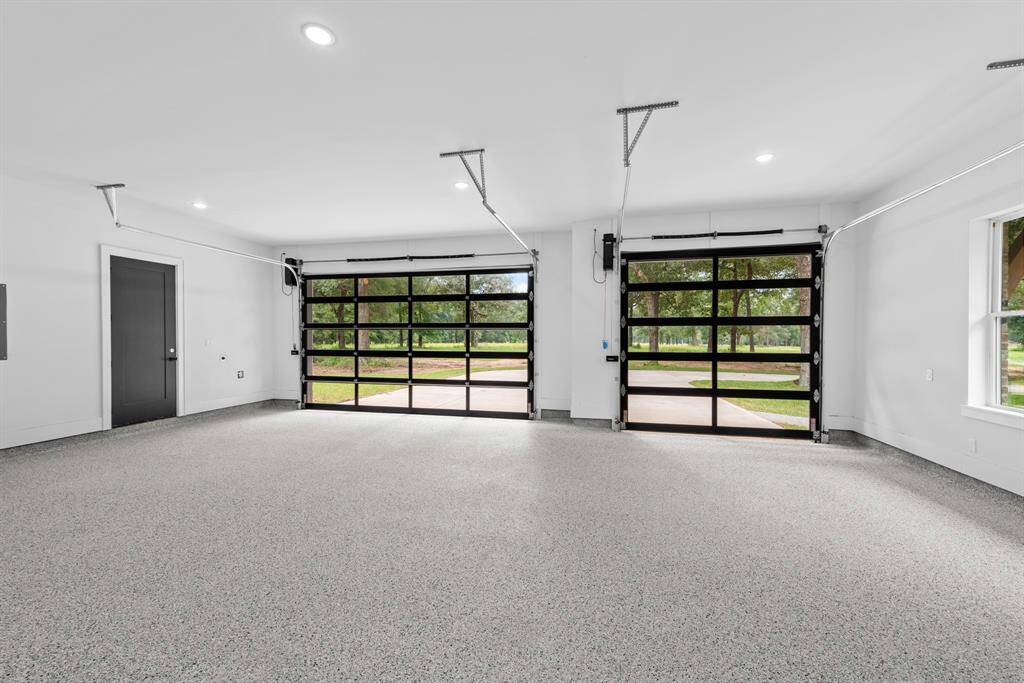 3 full car glass door garage space with epoxy flooring, exterior door to backyard and storage closet.