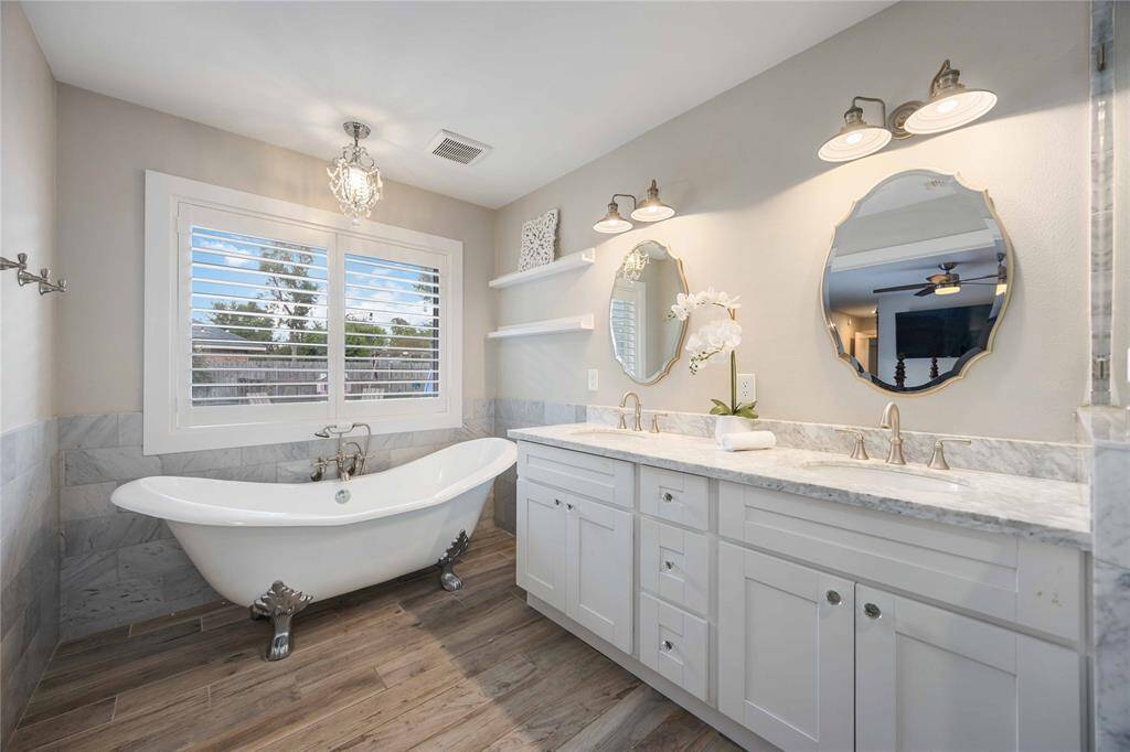 Featuring a stunning claw foot tub, tile surround, a dual sink vanity, and a frameless shower, you'll never want to leave the room.