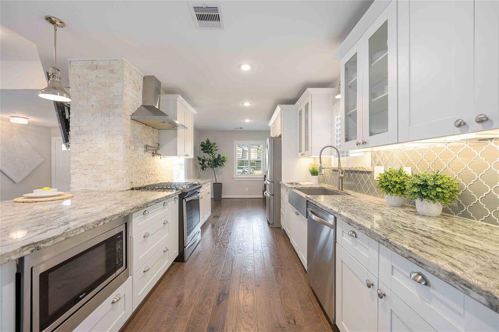 Stunning countertops and under-cabinet lighting meet a stone accent wall and a stylish backsplash to create a fabulous, gourmet kitchen. Notice the elegant glass front upper cabinets. All new Whirlpool appliances!