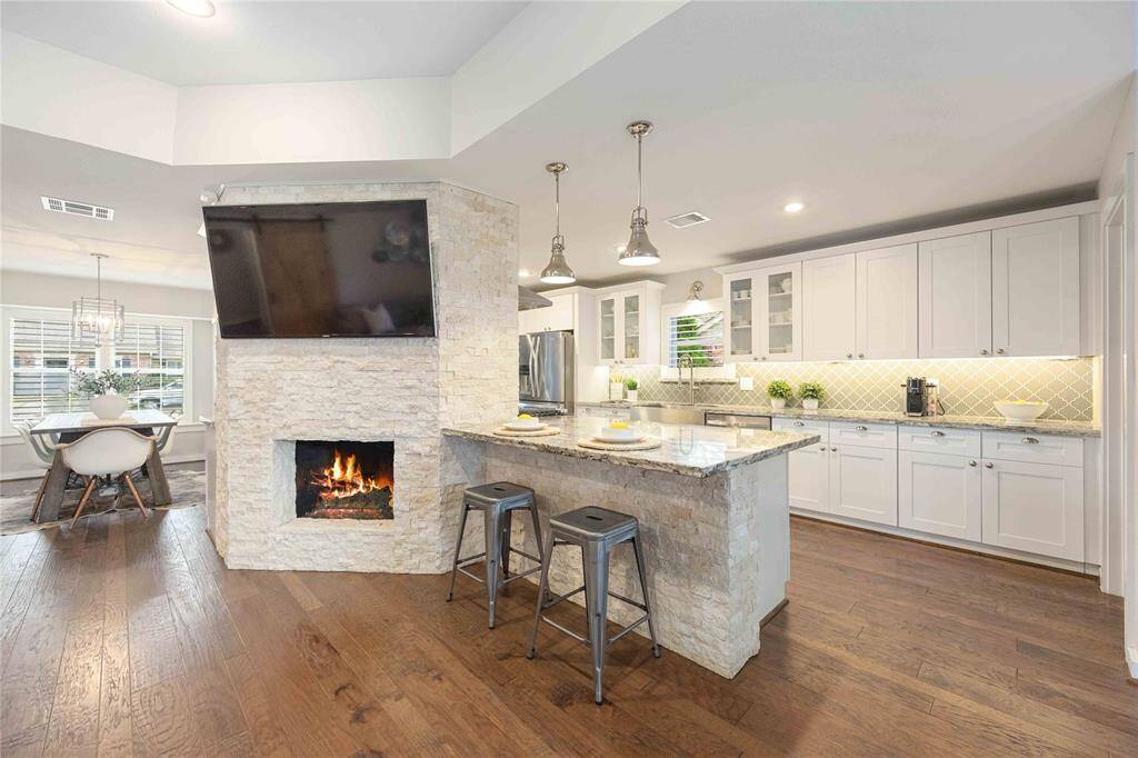The kitchen joins the family room at the convenient breakfast bar. Exquisite drop lights add an elegant touch.