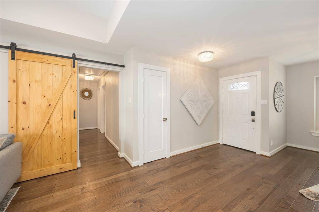A natural wood barn door conceals the hallway toward the bedrooms.