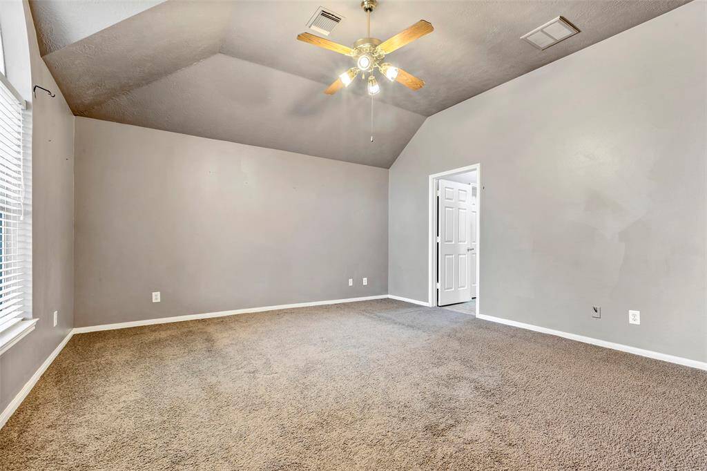 Primary room with a ceiling fan with lights, ample natural light from a large window, and an adjoining door leading to the primary bathroom.