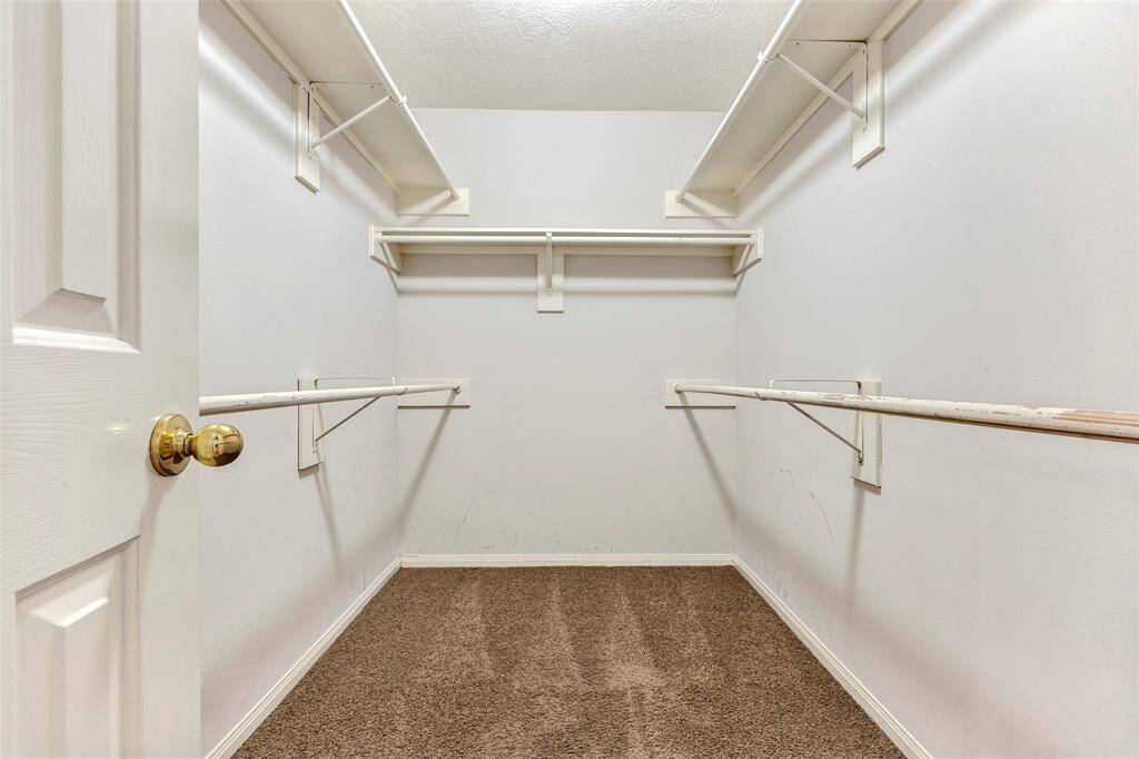 Spacious walk-in closet, with ample hanging rods, and shelves for storage.