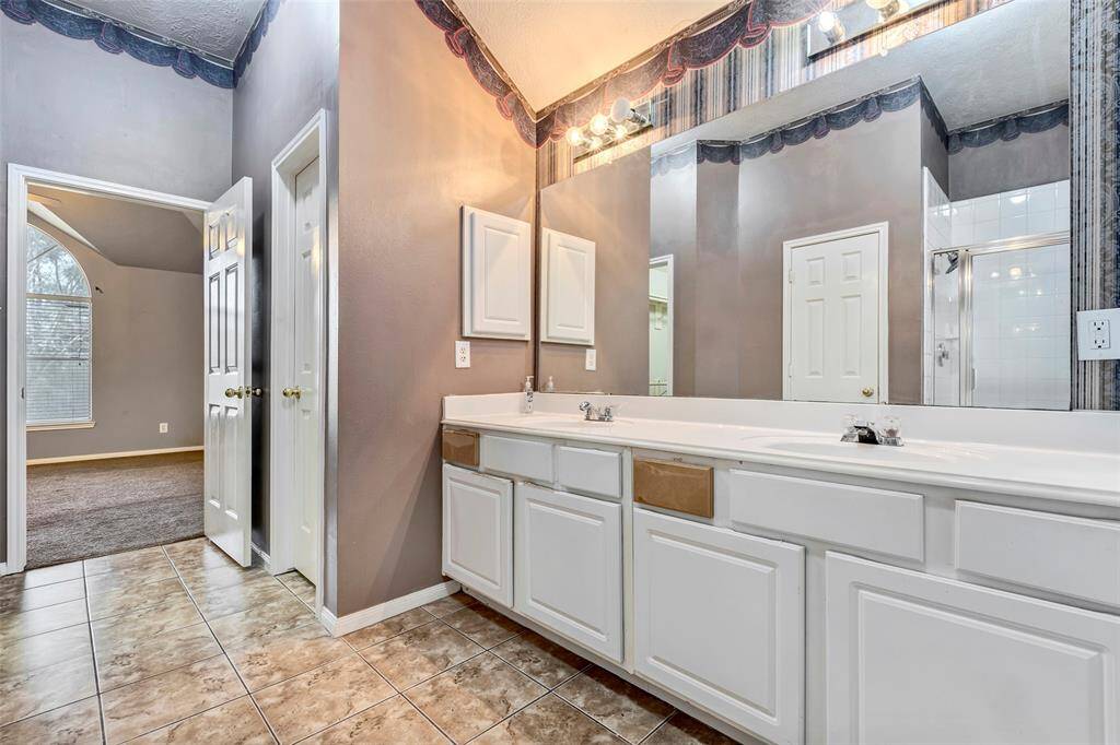 Primary bathroom with dual sinks, large mirrors, and ample cabinet space.  It offers a separate shower and a jetted jacuzzi.