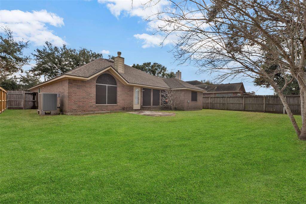 Spacious, well-maintained backyard. It features a fenced perimeter for privacy, a large lawn area, and mature trees.