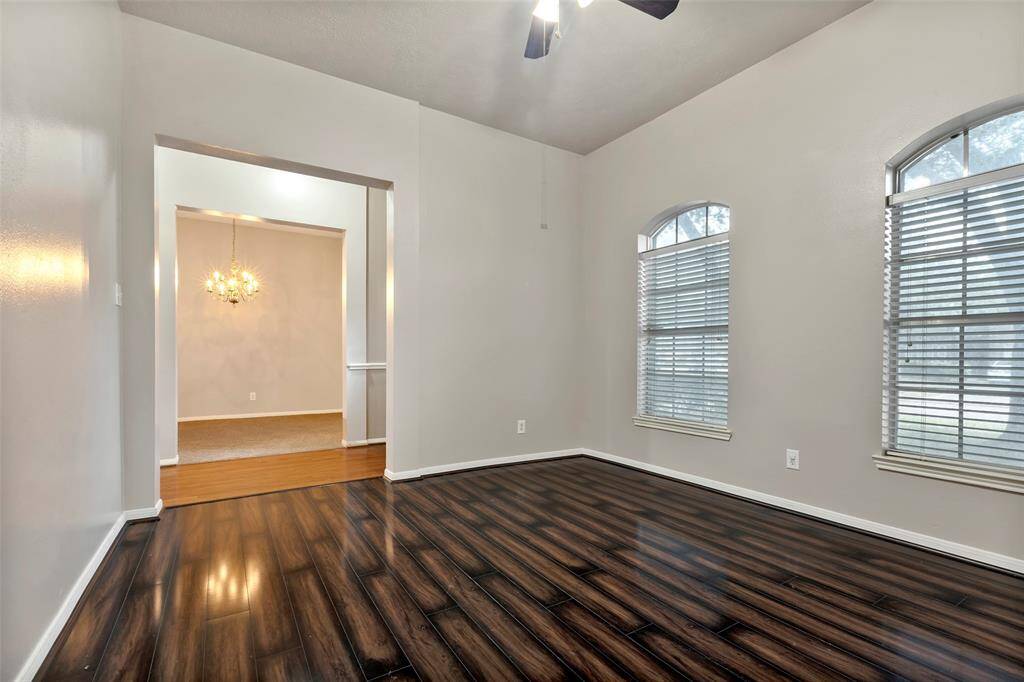 Office/study area has two large arched windows with blinds for ample natural light, and a ceiling fan.