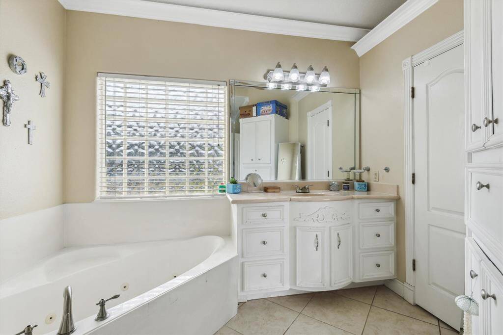 Primary bathroom with double sinks, built-in cabinets, jetted tub, walk in closet and separate shower.