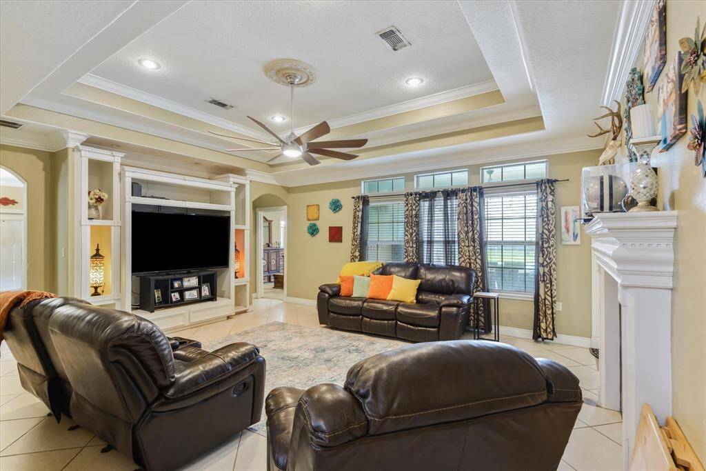 Living room with tiered ceilings, solid surface floors, built ins and fireplace.