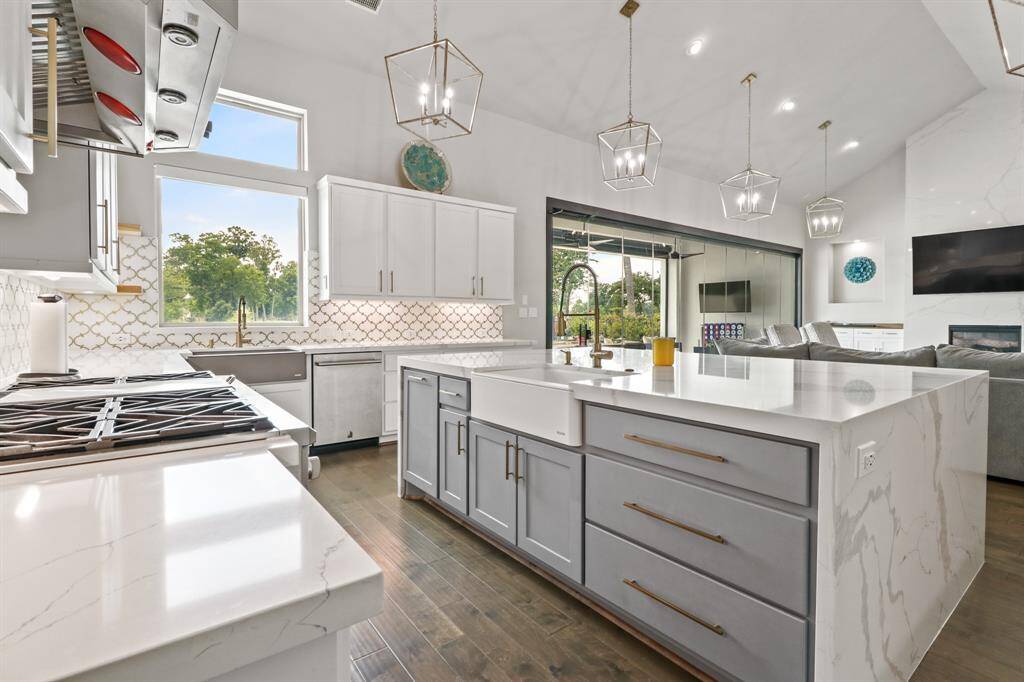 The waterfall edge island features a deep farmhouse sink, pots and pans drawers, and additional space for breakfast seating.