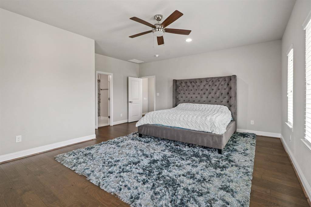 This spectacular secondary bedroom on the upper floor could serve as a second primary suite, ideal for multi-generational families! It features handsome hardwood flooring, a ceiling fan, large windows that flood the room with natural light, and access to an en suite bathroom.