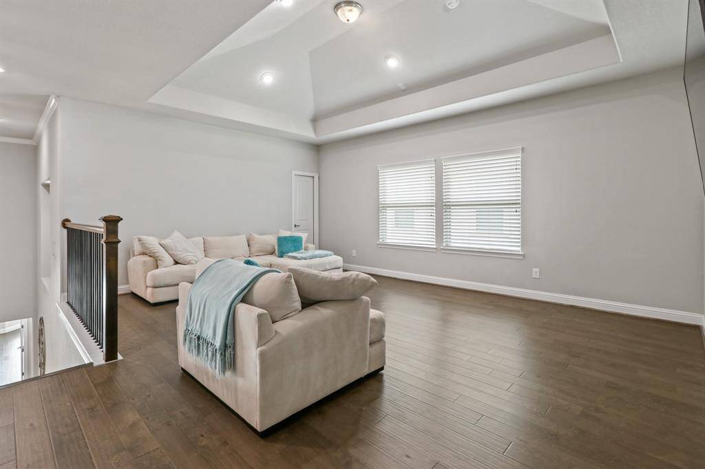 The expansive Game Room on the upper floor offers tray ceilings, hardwood flooring, and oversized windows that fill the space with abundant natural light.