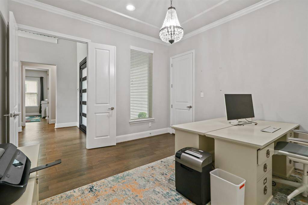 The Sophisticated Study showcases hardwood flooring, charming chandelier and double doors for privacy while working.