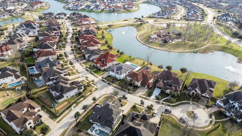 An impressive aerial view highlights the beautiful exterior of this home, with the serene lake directly behind. Just beyond your backyard, enjoy easy access to the nearby community park, offering even more opportunities for outdoor recreation. This prime location perfectly combines lakeside living with the convenience of neighborhood amenities!