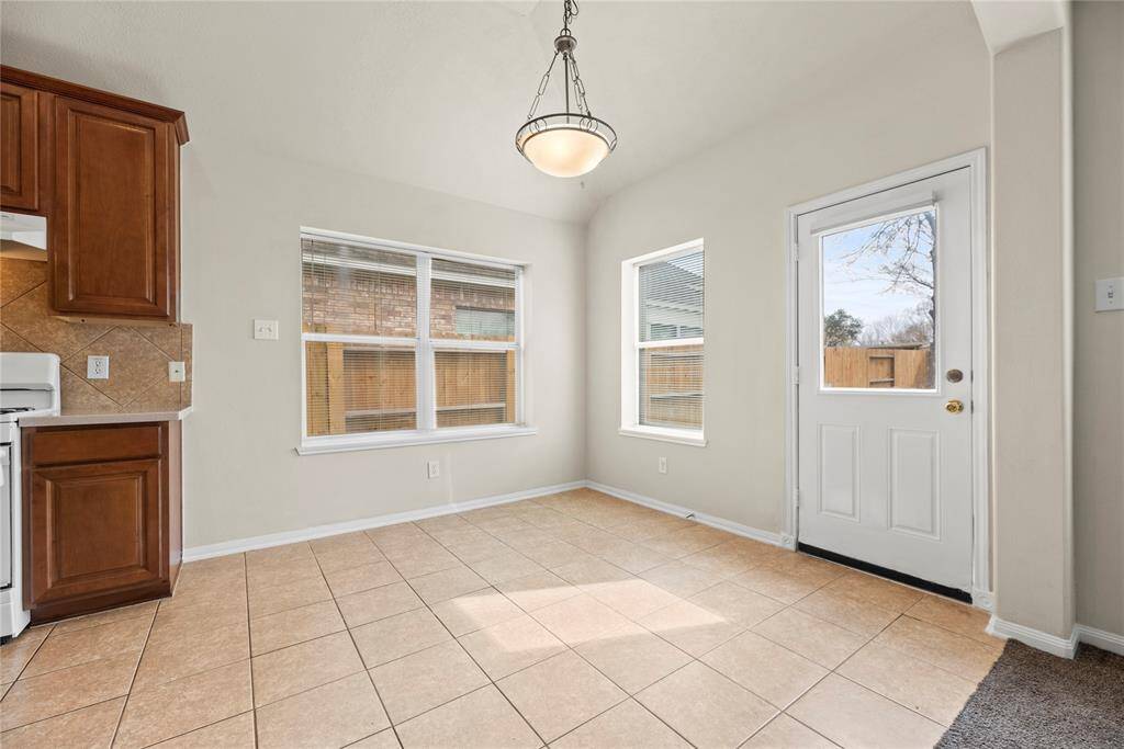 The breakfast room is ideal for a full-sized table and features easy care tile floors, large bright windows, overhead chandelier, and easy access to the backyard.