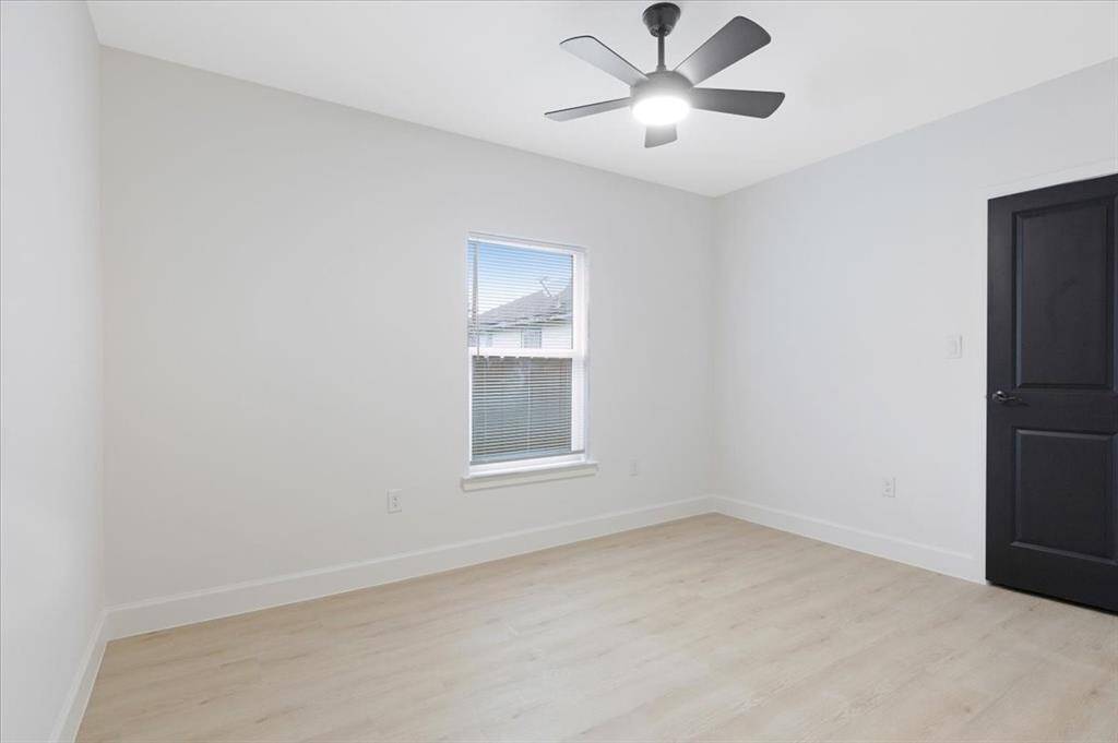 Spacious third bedroom with natural light and modern ceiling fan.