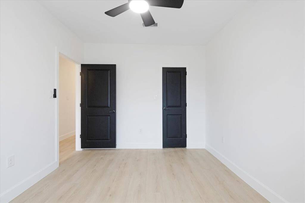 Spacious third bedroom with sleek black doors and natural light, perfect for a guest room or home office.