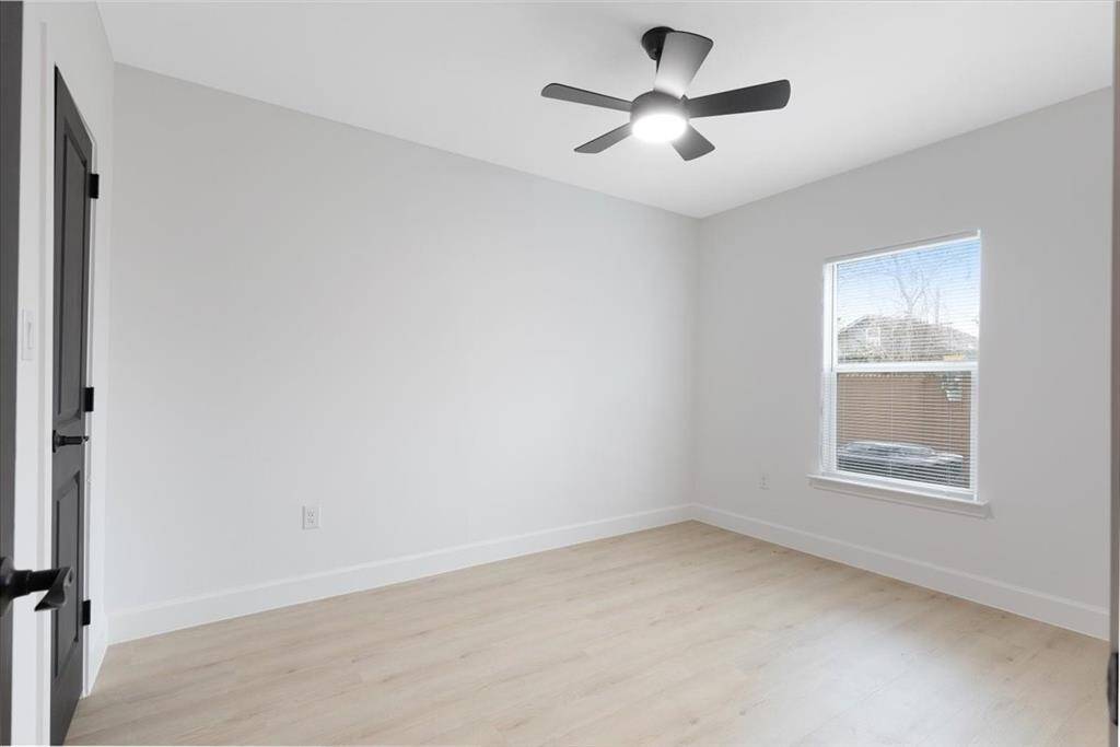 Spacious fourth bedroom with natural light and modern ceiling fan, perfect for guests or a home office.